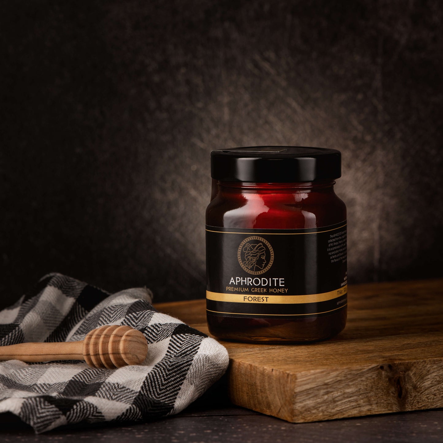 Greek Raw Forest Honey in a 500g glass jar in dark / black background. Jar presented on the side. 100% Pure Honey. Aphrodite Honey. Aphrodite Premium Greek Honey.