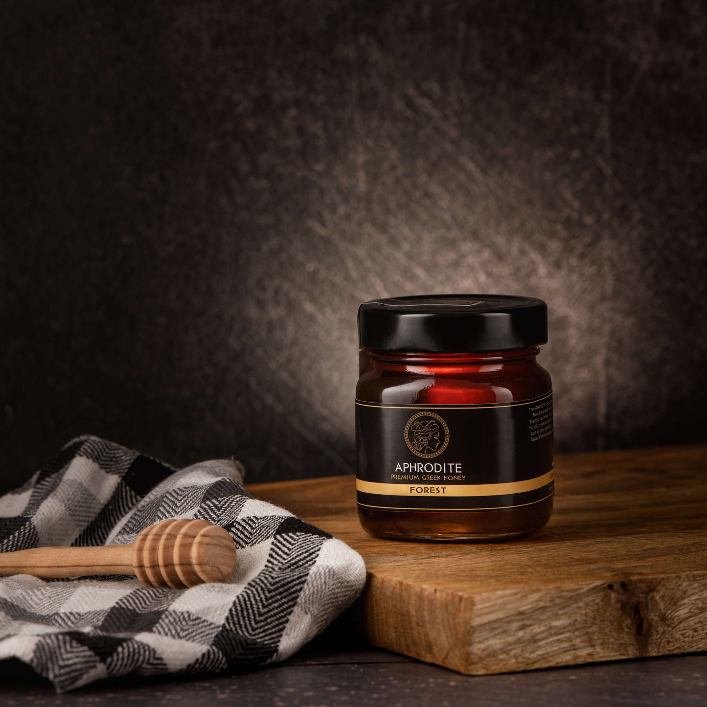 Greek Raw Forest Honey in a 250g glass jar in dark / black background. Jar presented on the side. 100% Pure Honey. Aphrodite Honey. Aphrodite Premium Greek Honey.