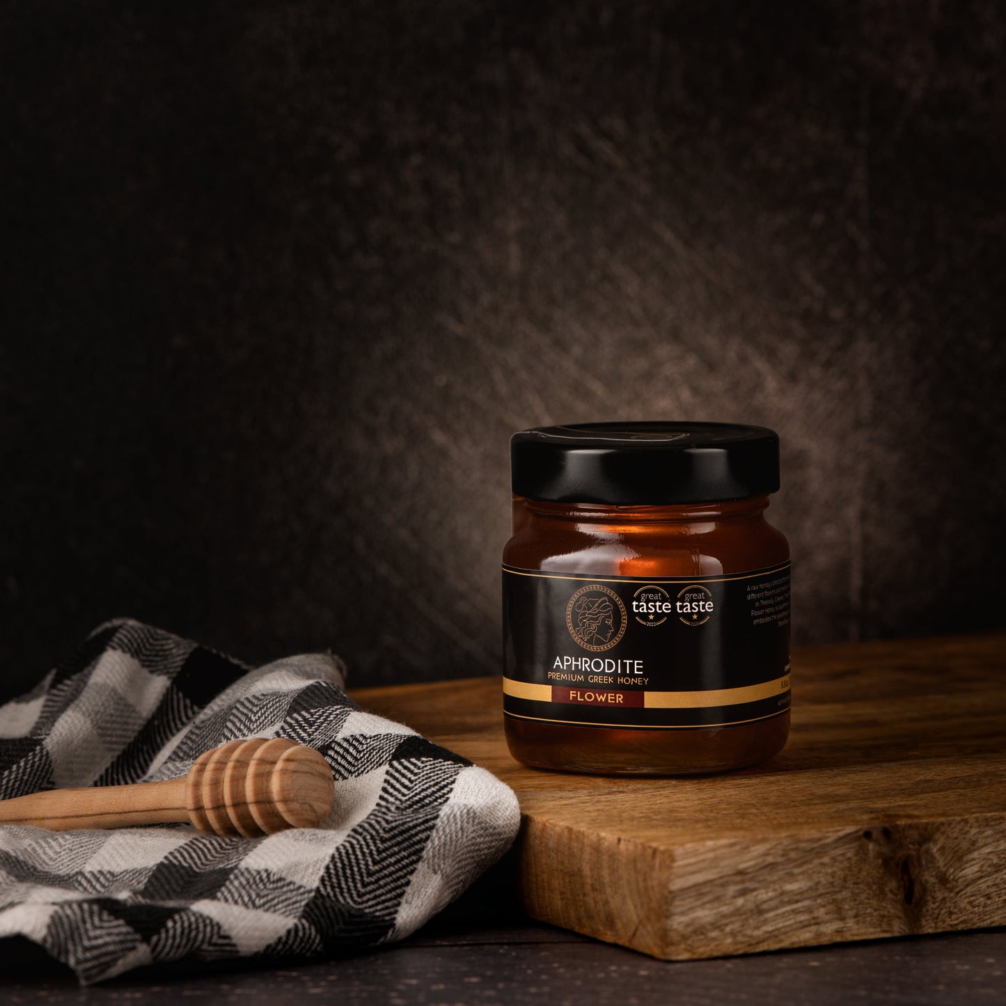 Greek Raw Flower / Blossom Honey in a 250g glass jar in dark / black background. Jar presented on the side. 100% Pure Honey. Aphrodite Honey. Aphrodite Premium Greek Honey. Great Taste 1 star.