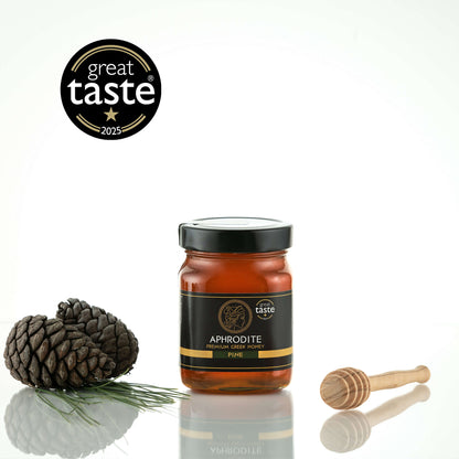 Aphrodite Raw Pine Honey 480g jar with pinecones, a pine sprig and honey dipper, Great Taste 2025 award badge, white background