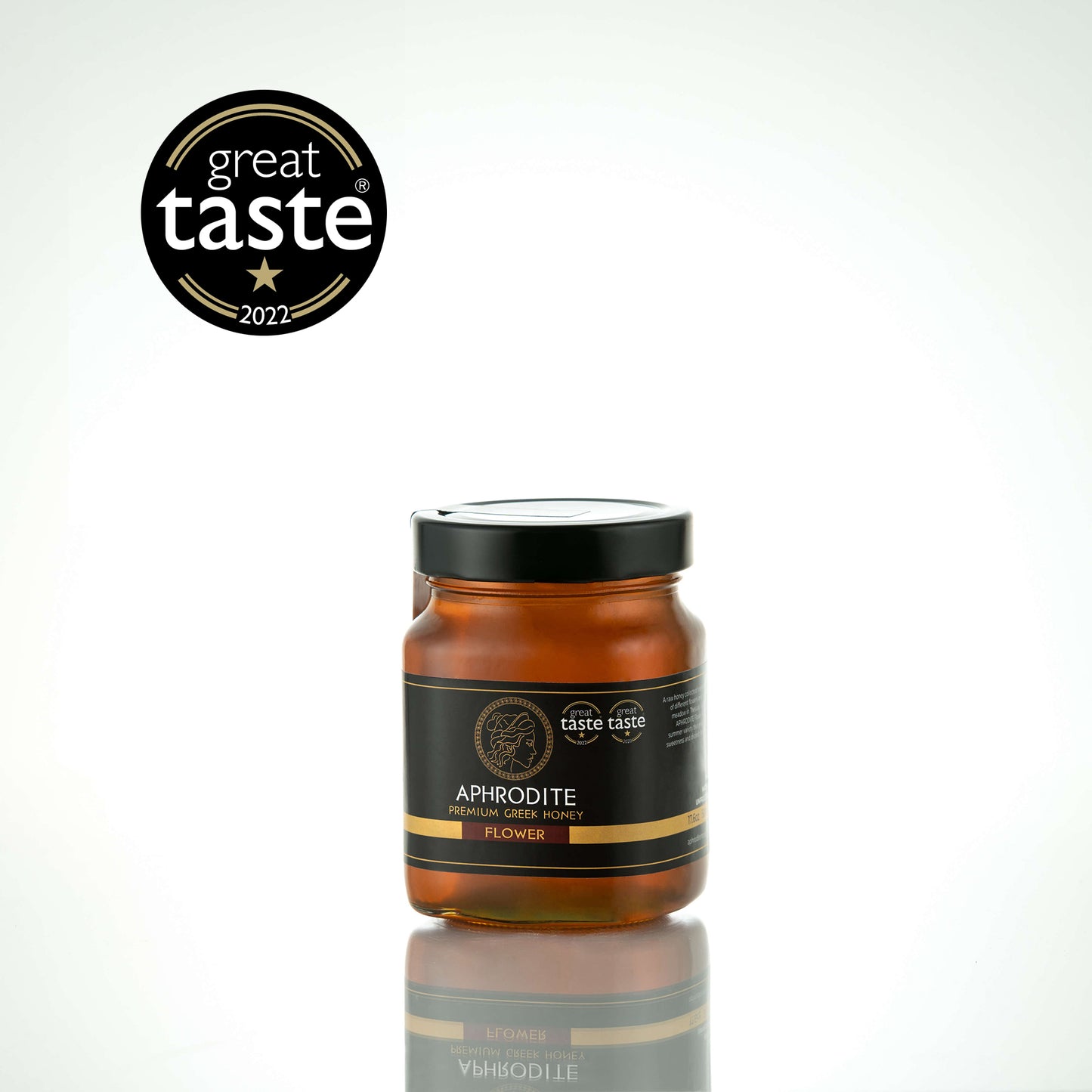 Aphrodite Raw Flower Honey 480g glass jar with black lid on a white reflective background, Great Taste 2022 award badge