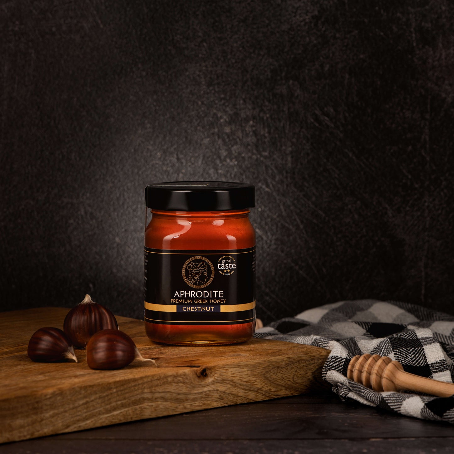Aphrodite Raw Chestnut Honey 480g jar on rustic wooden board with whole chestnuts and honey dipper