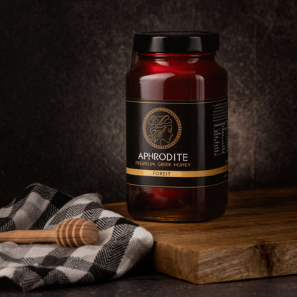 Greek Raw Forest Honey in a 950g glass jar in dark / black background. Jar presented on the side. 100% Pure Honey. Aphrodite Honey. Aphrodite Premium Greek Honey.